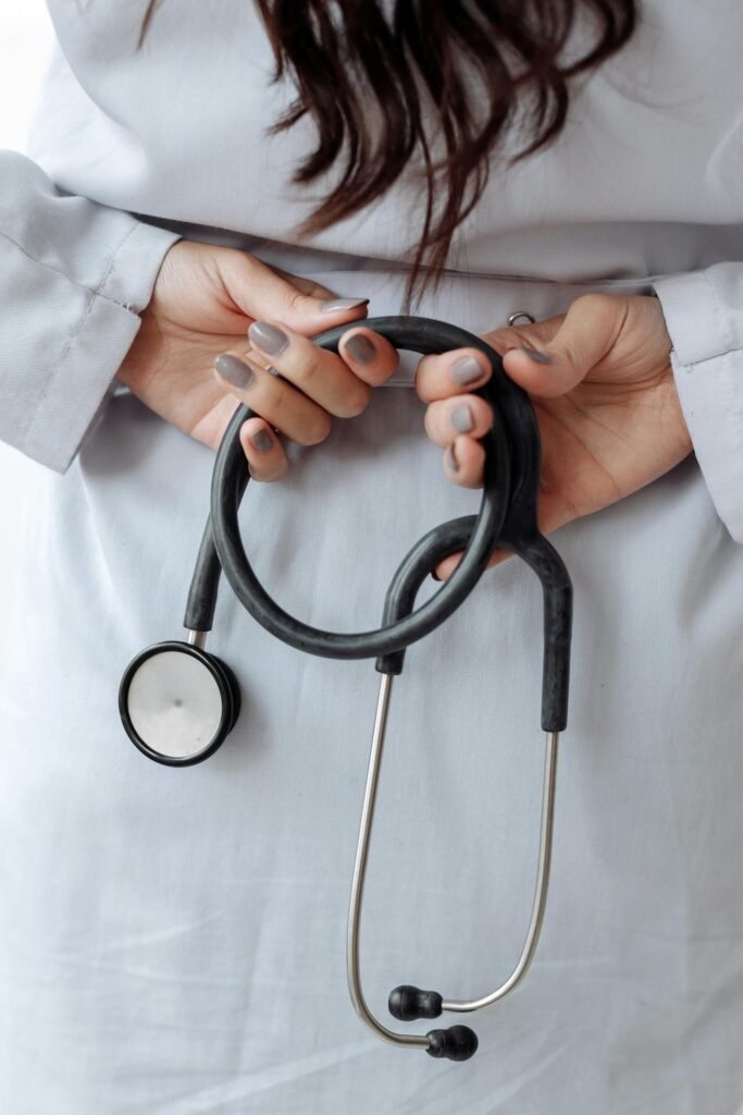 Close-up shot of a doctor holding a stethoscope with both hands, wearing a white coat.